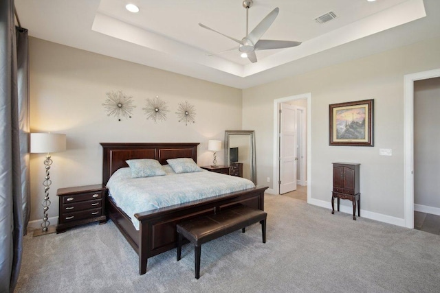 bedroom featuring light carpet, baseboards, visible vents, and a raised ceiling