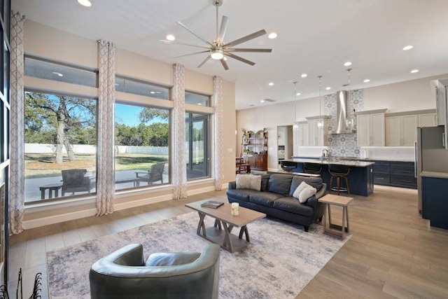 living room featuring light wood-type flooring, plenty of natural light, baseboards, and recessed lighting