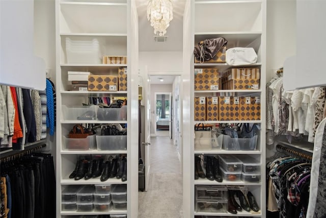 spacious closet featuring carpet, visible vents, and an inviting chandelier