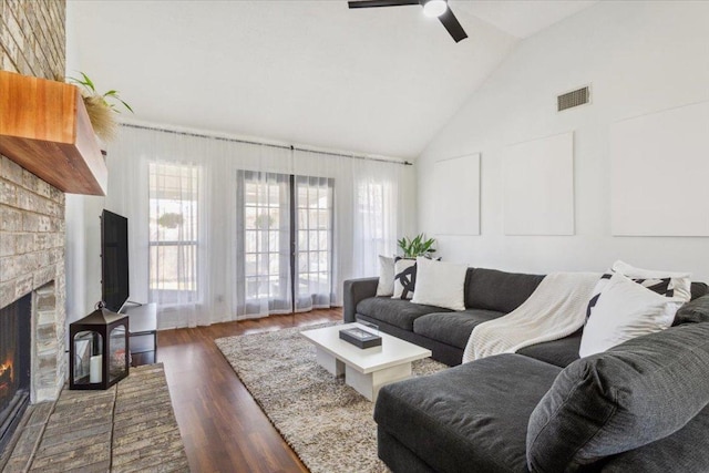 living room featuring visible vents, ceiling fan, dark wood-type flooring, a fireplace, and high vaulted ceiling