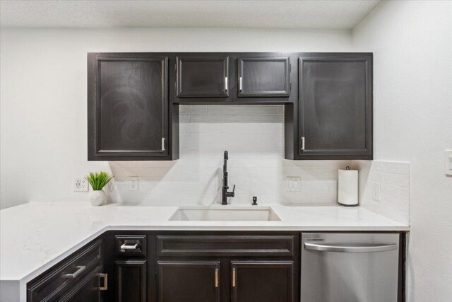 kitchen featuring tasteful backsplash, light countertops, dishwasher, and a sink