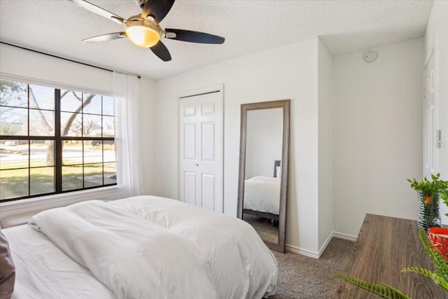 carpeted bedroom featuring ceiling fan, baseboards, and a textured ceiling