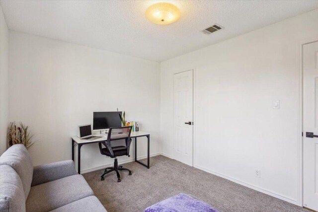 office area with baseboards, a textured ceiling, visible vents, and carpet flooring