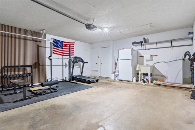 workout room featuring a garage, attic access, and a textured ceiling