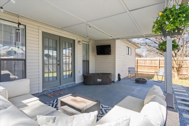 view of patio with french doors, an outdoor living space with a fire pit, and fence