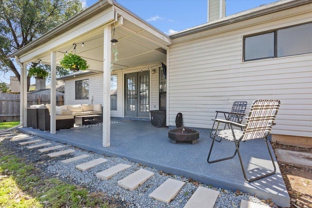 view of patio / terrace featuring french doors, an outdoor living space with a fire pit, and fence