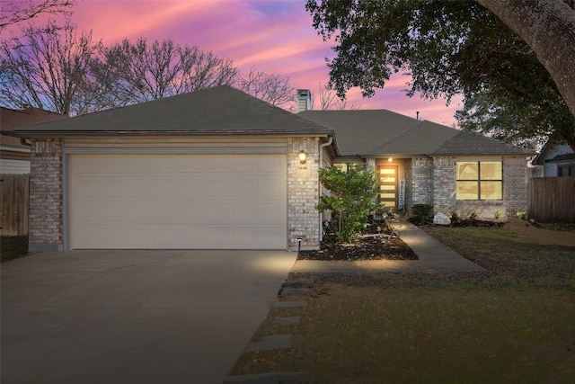 view of front of home with concrete driveway, brick siding, fence, and an attached garage