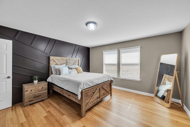 bedroom featuring a textured ceiling, light wood finished floors, and baseboards