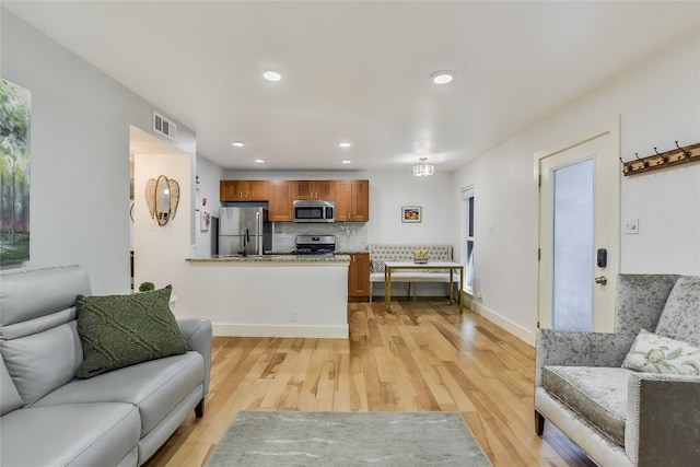 living area featuring recessed lighting, visible vents, light wood-style flooring, and baseboards