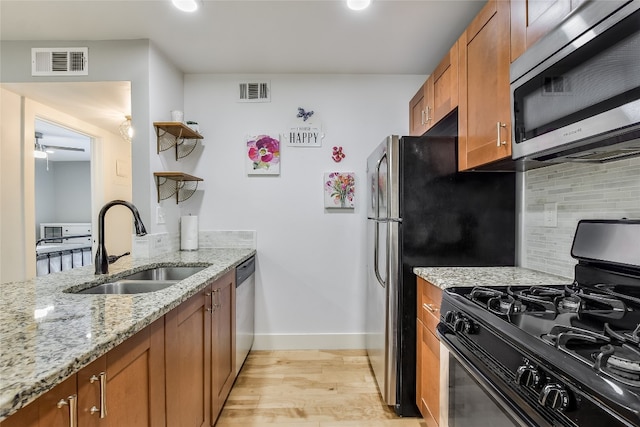 kitchen with visible vents, light stone counters, appliances with stainless steel finishes, brown cabinets, and a sink