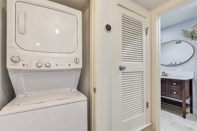 clothes washing area featuring marble finish floor and stacked washer / drying machine