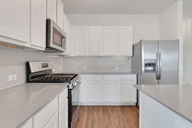 kitchen featuring light wood-type flooring, white cabinetry, stainless steel appliances, and light countertops