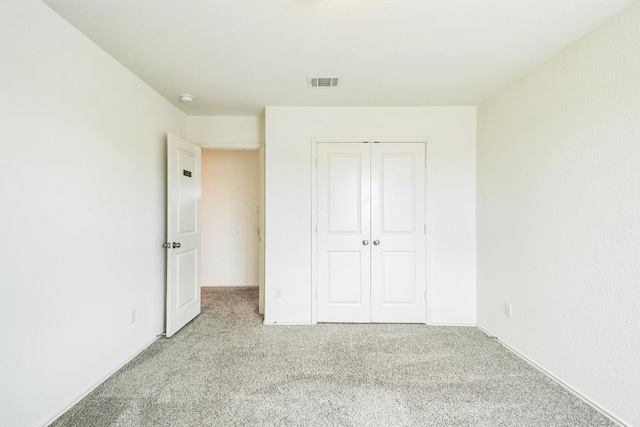 unfurnished bedroom with carpet floors, a closet, and visible vents