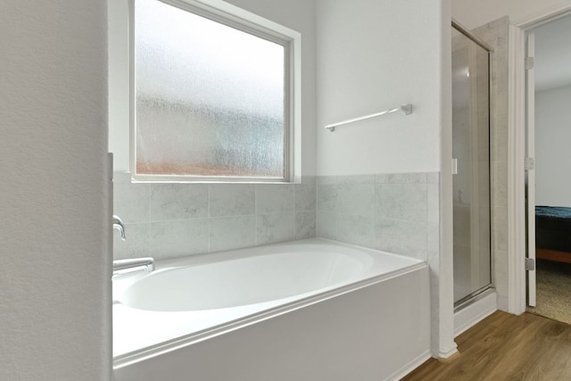 bathroom featuring wood finished floors, a shower stall, and a bath