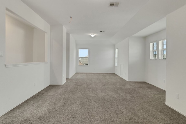 spare room featuring carpet flooring, visible vents, and a healthy amount of sunlight