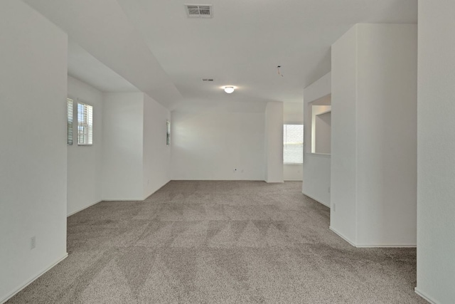 unfurnished room featuring a wealth of natural light, visible vents, and carpet flooring