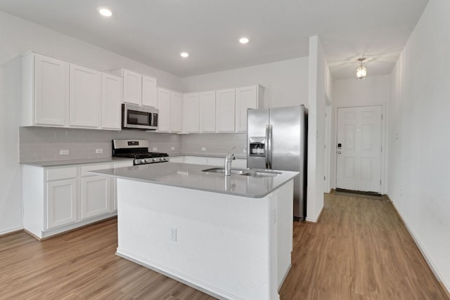 kitchen featuring white cabinets, light wood finished floors, stainless steel appliances, and a sink