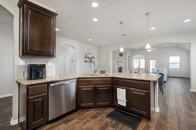 kitchen featuring arched walkways, a sink, stainless steel dishwasher, and dark brown cabinets