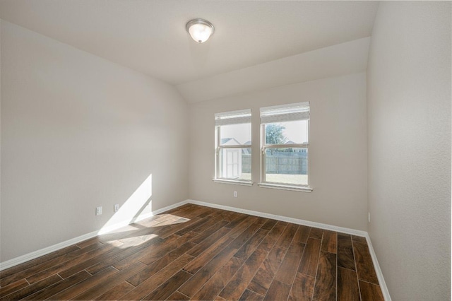 spare room with dark wood-style floors, lofted ceiling, and baseboards