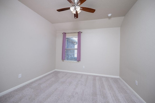 carpeted spare room with lofted ceiling, ceiling fan, and baseboards