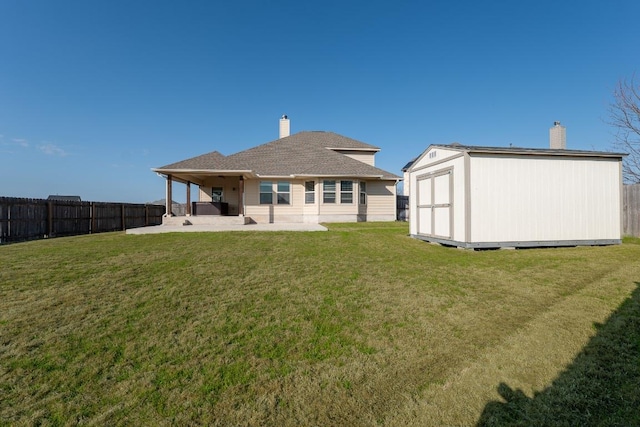 back of property with an outbuilding, a patio, a chimney, a storage unit, and a fenced backyard