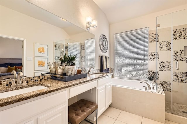 bathroom featuring a stall shower, tile patterned flooring, a garden tub, and a sink