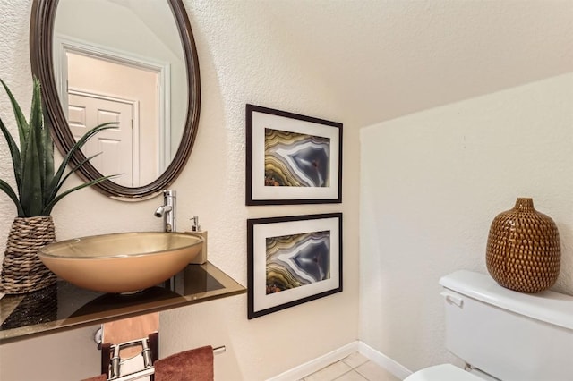 half bath featuring toilet, baseboards, a sink, and tile patterned floors