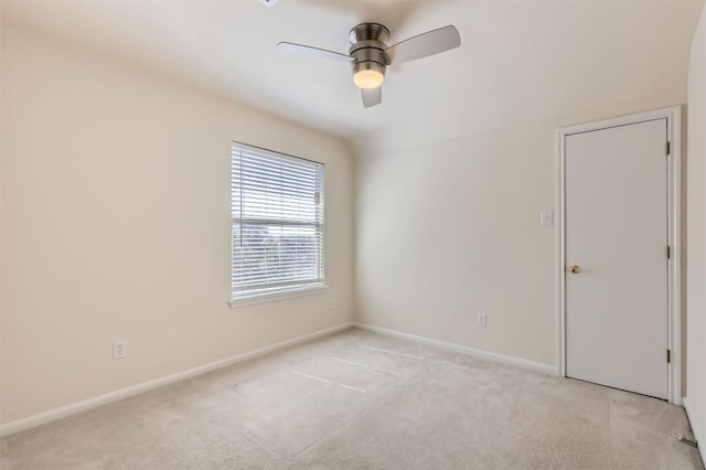 spare room with light carpet, ceiling fan, and baseboards