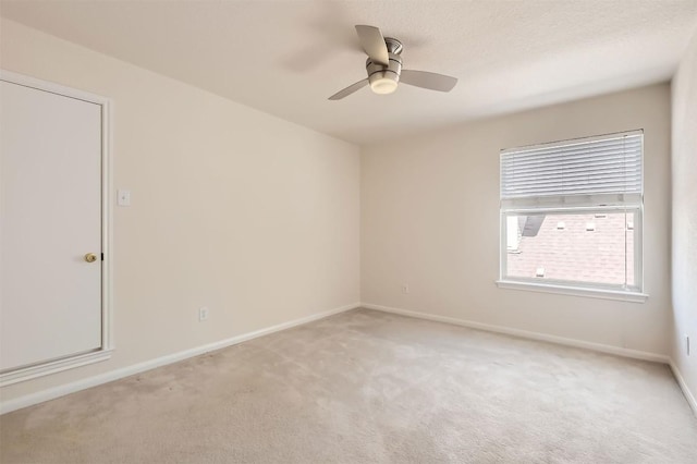 spare room featuring a textured ceiling, baseboards, a ceiling fan, and light colored carpet