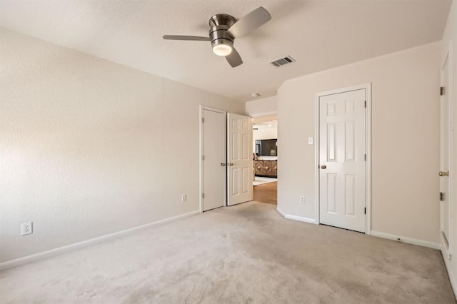 unfurnished bedroom featuring light carpet, a ceiling fan, visible vents, and baseboards