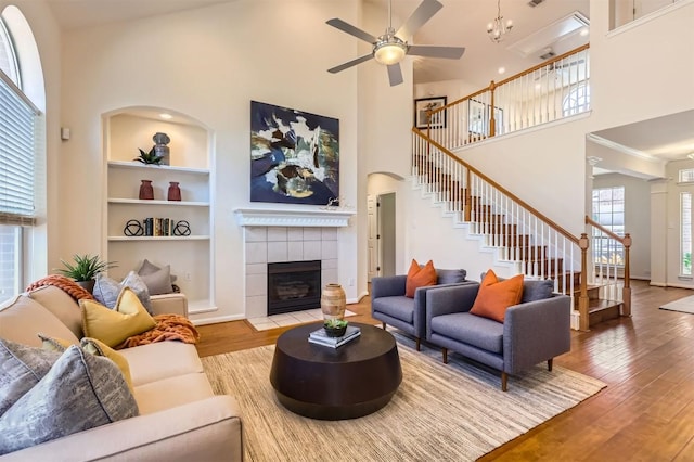 living area with stairs, built in features, wood finished floors, and a tiled fireplace