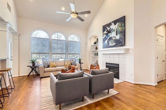 living area with high vaulted ceiling, a wealth of natural light, a fireplace, and hardwood / wood-style floors