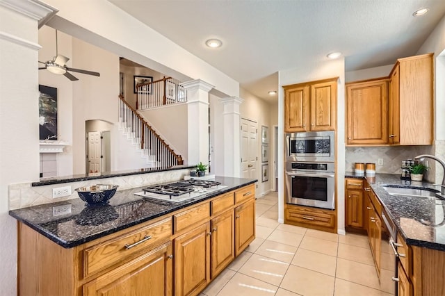 kitchen featuring backsplash, appliances with stainless steel finishes, light tile patterned flooring, a sink, and ornate columns