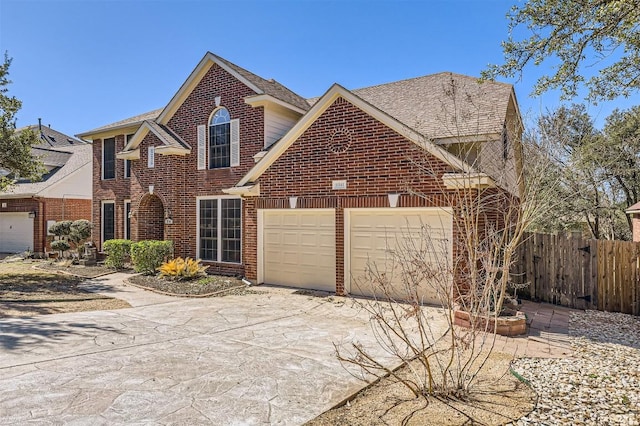 traditional home with brick siding, roof with shingles, concrete driveway, an attached garage, and fence