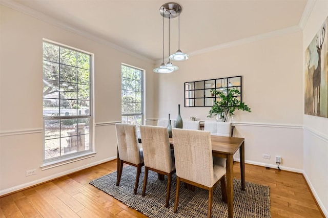 dining room featuring light wood-style floors, crown molding, and baseboards