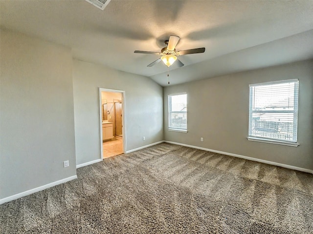 unfurnished bedroom featuring carpet, lofted ceiling, ensuite bathroom, ceiling fan, and baseboards