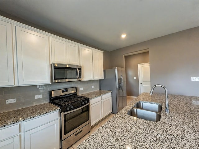 kitchen featuring stainless steel appliances, white cabinets, a sink, and tasteful backsplash