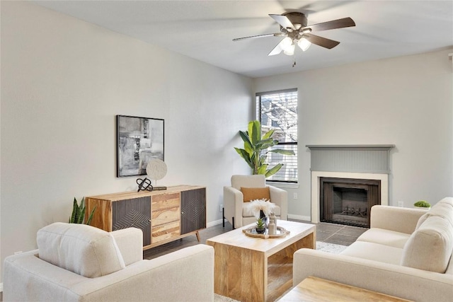 living room featuring ceiling fan, a fireplace, and baseboards