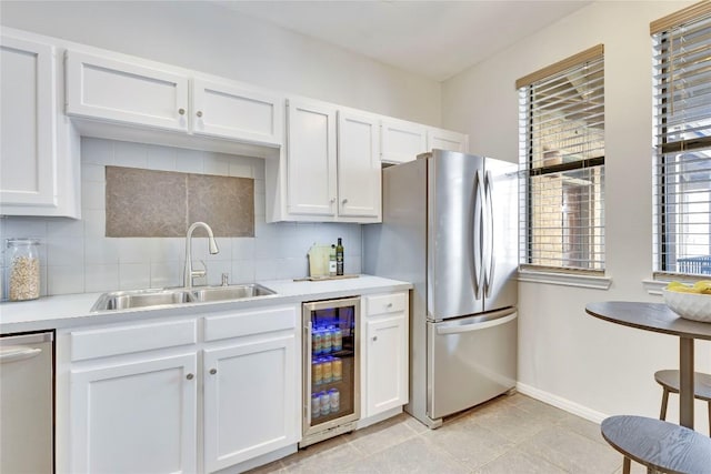 kitchen featuring wine cooler, backsplash, appliances with stainless steel finishes, white cabinetry, and a sink