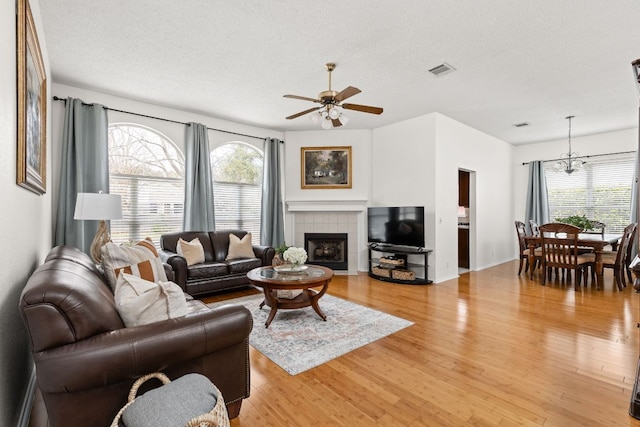 living area with a fireplace, visible vents, plenty of natural light, and light wood finished floors