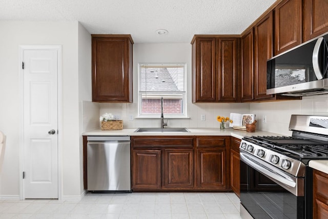 kitchen featuring stainless steel appliances, a sink, and light countertops