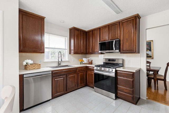 kitchen featuring stainless steel appliances, light countertops, a sink, and tasteful backsplash