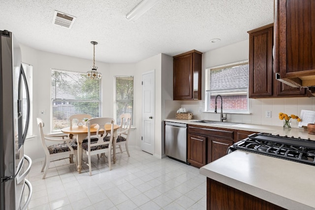 kitchen with a sink, visible vents, light countertops, appliances with stainless steel finishes, and decorative backsplash