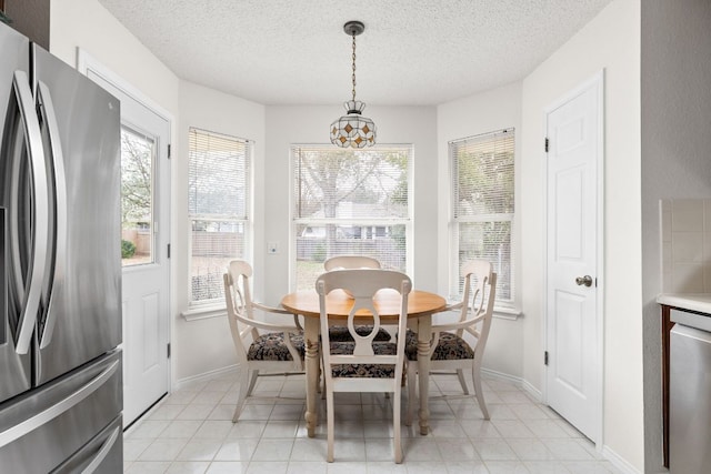 dining area with a textured ceiling, light tile patterned flooring, and baseboards