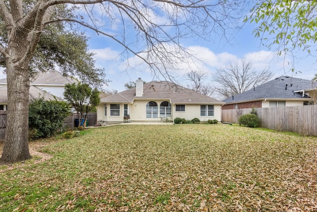 rear view of property with a fenced backyard, a chimney, a shingled roof, and a yard