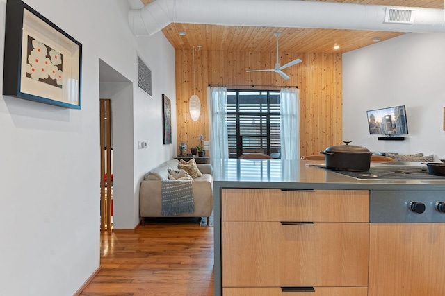 kitchen with wood finished floors, visible vents, light brown cabinetry, wood walls, and modern cabinets