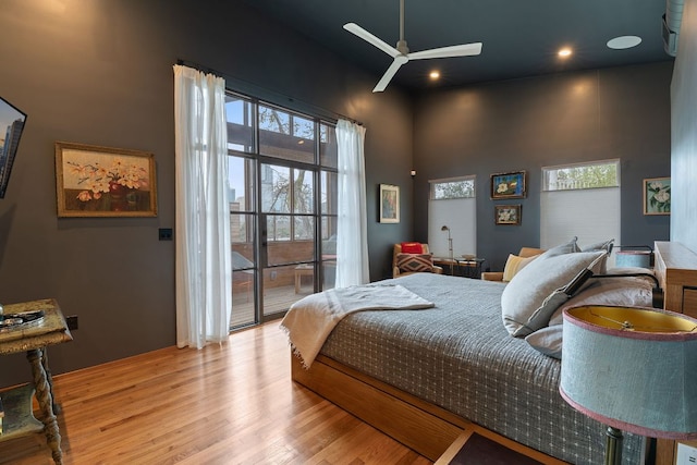 bedroom with access to exterior, a high ceiling, and wood finished floors