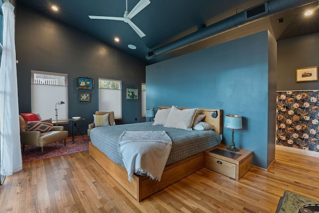 bedroom featuring ceiling fan, high vaulted ceiling, wood finished floors, and visible vents