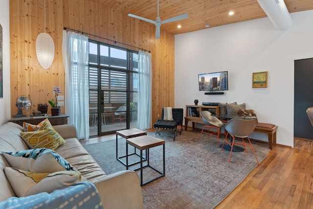 living area featuring wooden ceiling, hardwood / wood-style floors, beamed ceiling, a high ceiling, and wood walls