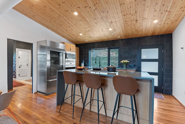 kitchen featuring light wood-style floors, wood ceiling, stainless steel appliances, and a center island